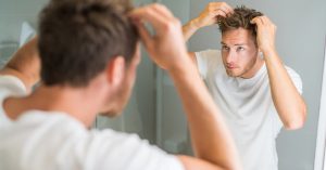 male checking hair in mirror