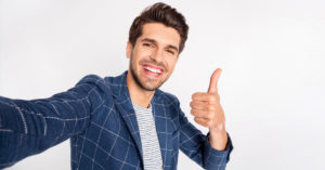 happy smiling man with full head of hair giving a thumbs up