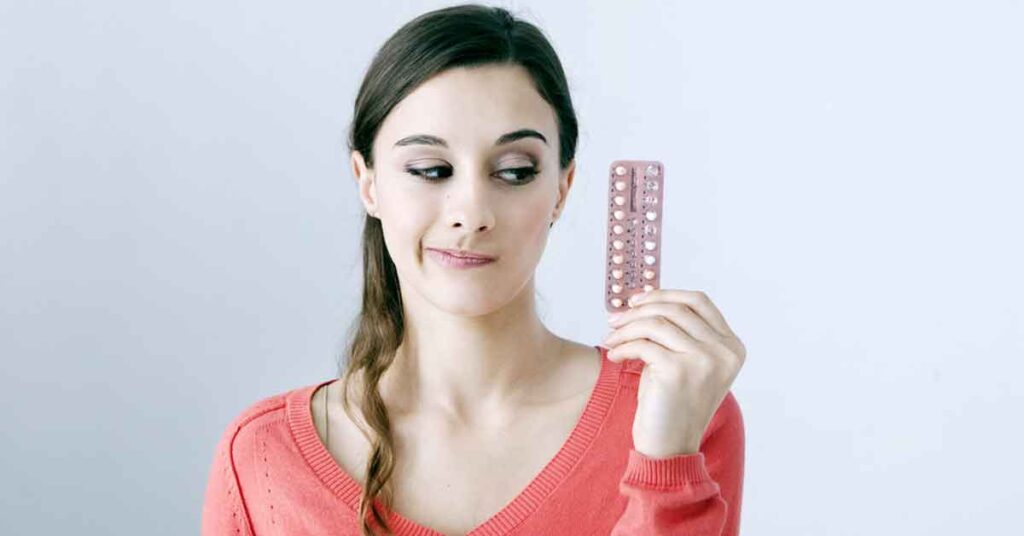 woman holding birth control pills